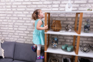 Cute,Toddler,Girl,Standing,On,Sofa,And,Reaching,For,Toys
